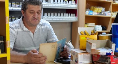 Bakkal kitap okuma tutkusunu iş yerinde de sürdürüyor