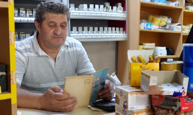 Bakkal kitap okuma tutkusunu iş yerinde de sürdürüyor